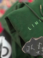 Load image into Gallery viewer, Close-up of Limitless hunter green hoodie front print with partial Limitless text graphic in non-PVC ink