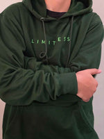 Load image into Gallery viewer, Model wearing Limitless hunter green hoodie in relaxed pose, three-quarter front angle