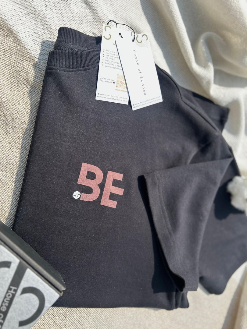 BeLeaver charcoal black oversized men’s t-shirt folded and focusing on the front "BE" print