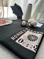 Load image into Gallery viewer, Hunter green  'Honor &amp; Harmony' t-shirt from House of SwaSha folded with cotton and a white curtain in the background.