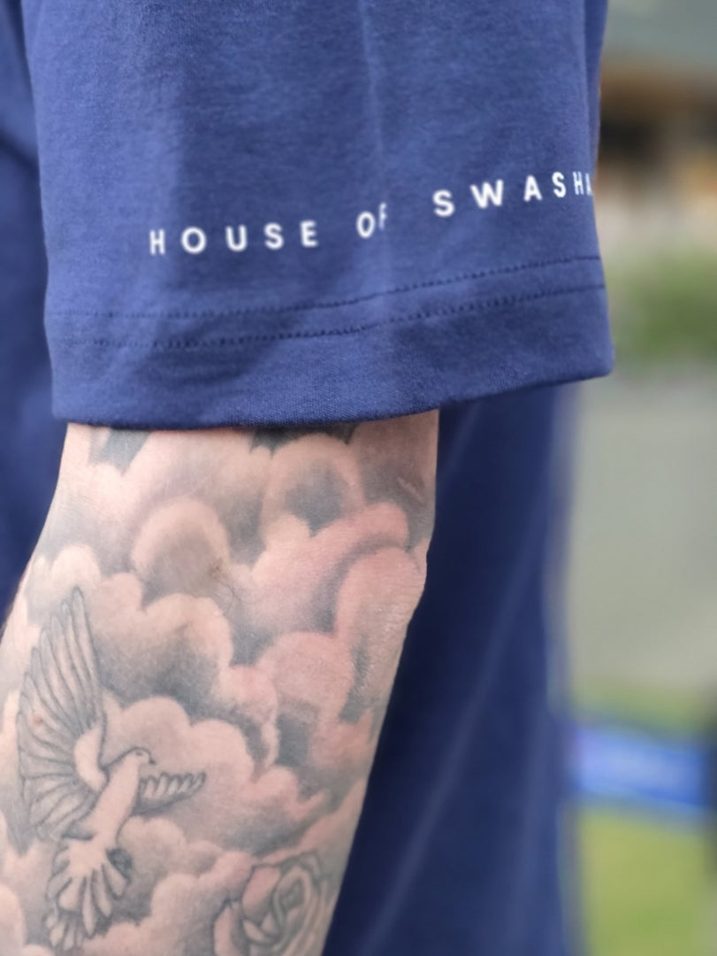 Navy blue t-shirt with 'House of Swasha' text, tattooed arm visible